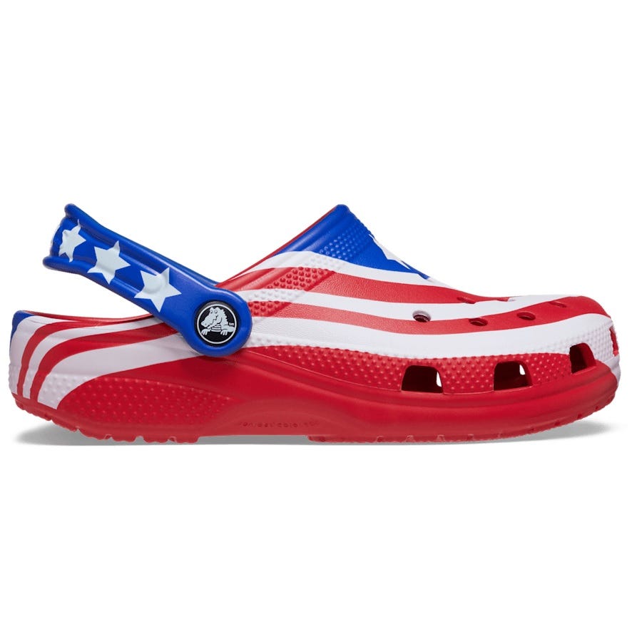 A Crocs clog with an American flag design, featuring red, white, and blue colors with stars and stripes.