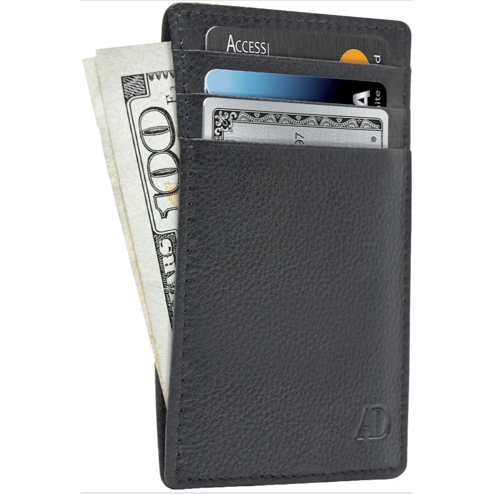 A black leather card holder with three card slots, displaying two credit cards and a $100 bill. Initials \“AD\“ are embossed on the bottom corner.