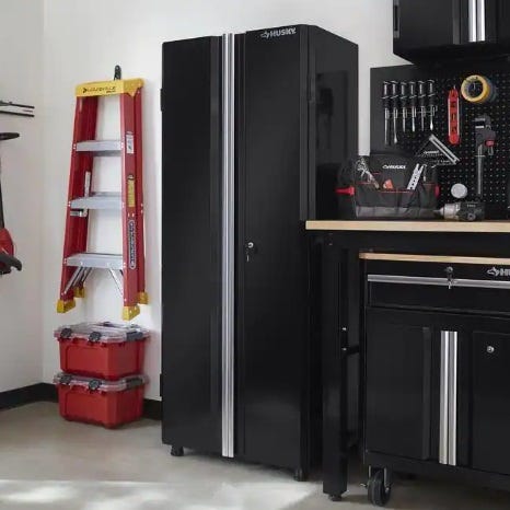 A black tool storage cabinet, a red and yellow ladder, and a red portable toolbox.