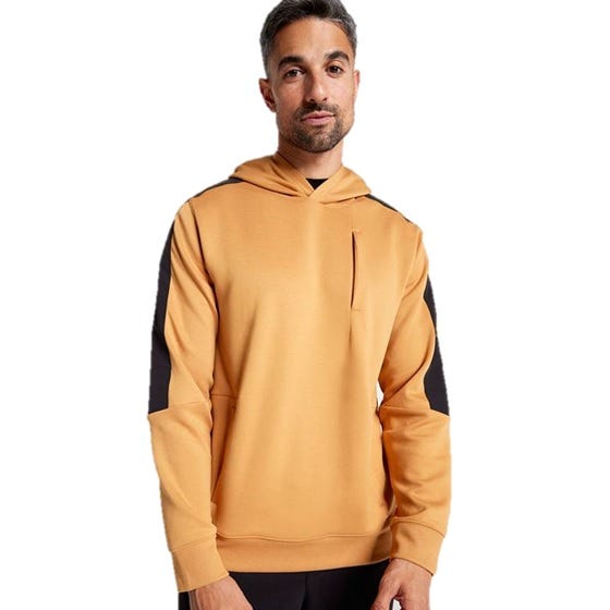 A man is wearing a mustard-colored hoodie with black accents on the shoulders and sleeves. The hoodie features a small chest pocket and has a casual, sporty style.