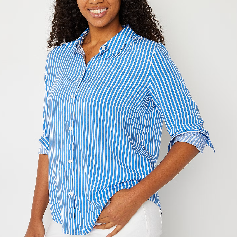 A woman wearing a blue and white striped, button-up shirt with rolled-up sleeves.