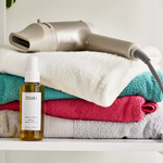 A hair dryer, colored towels, and a bottle of wave spray are visible.