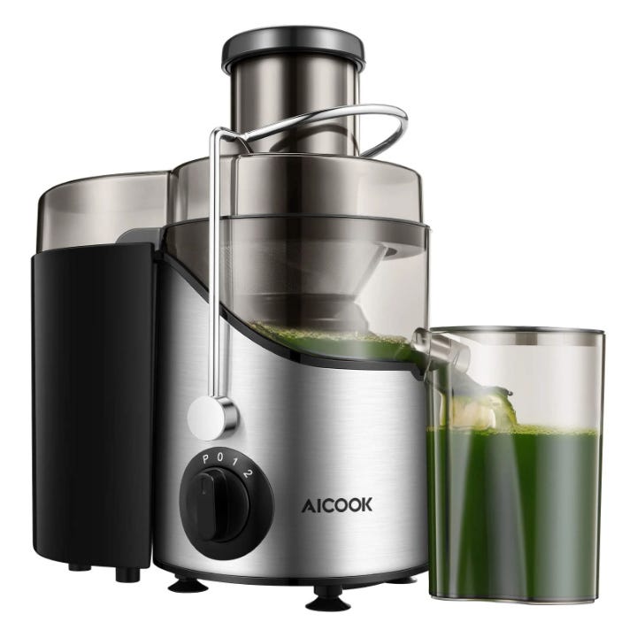 Stainless steel juicer with a black accent, pouring green juice into a glass.