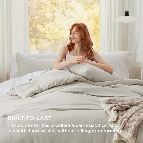 A woman sits on a bed with a pale comforter set, which includes pillows, and a text overlay highlighting its durability and resistance to pilling or deforming with washing. A knitted throw is placed at the foot of the bed.