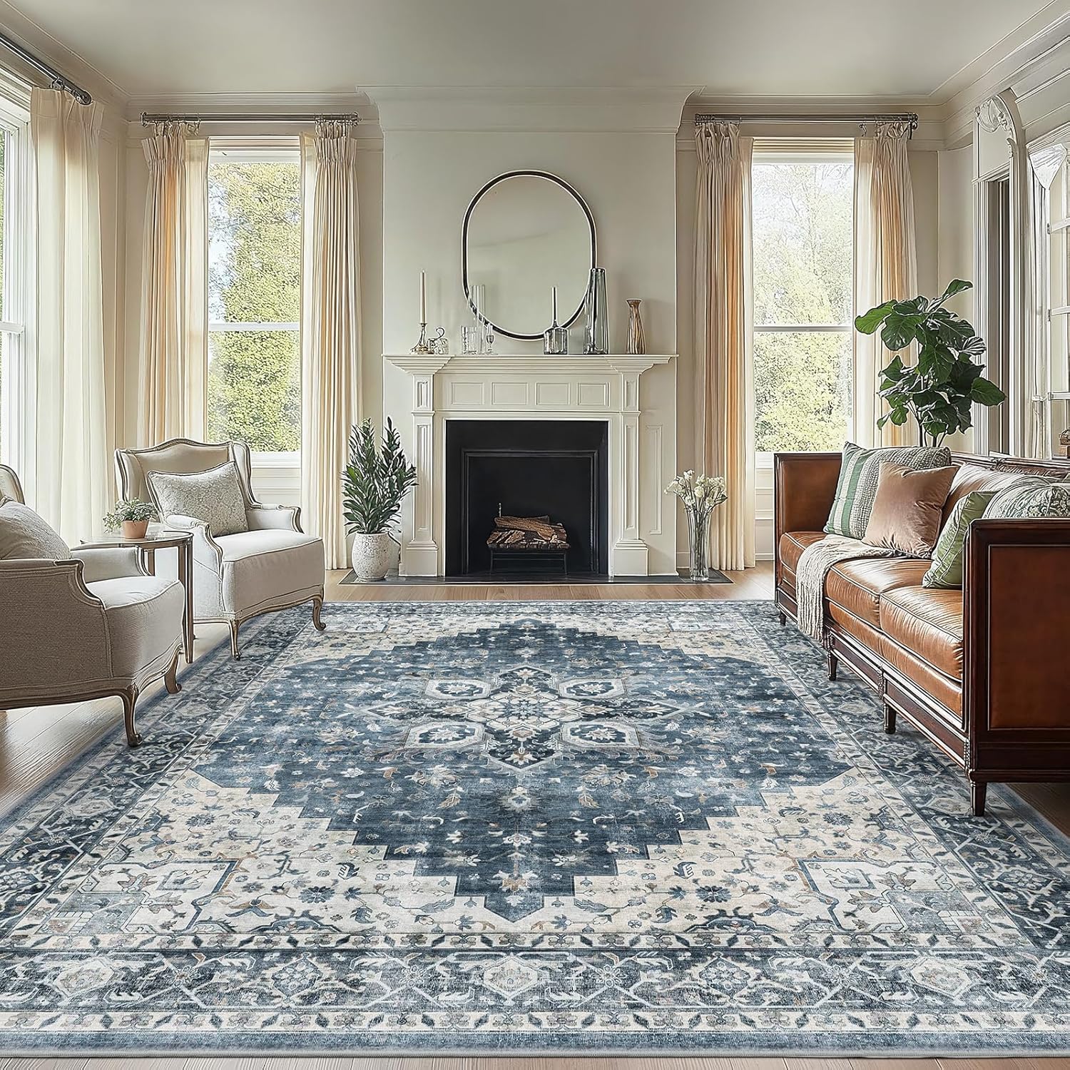A living room with a large patterned area rug in blue and white tones, placed between a sofa and armchairs in front of a fireplace with a circular mirror above.