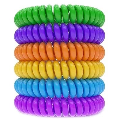 Colorful coil hair ties stacked in a rainbow sequence: green, purple, orange, yellow, blue, and pink.