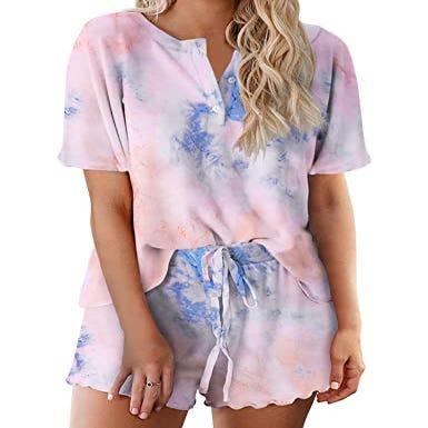 A tie-dye lounge set featuring a V-neck short-sleeve top and matching shorts with a drawstring waist, in pastel pink and blue hues.