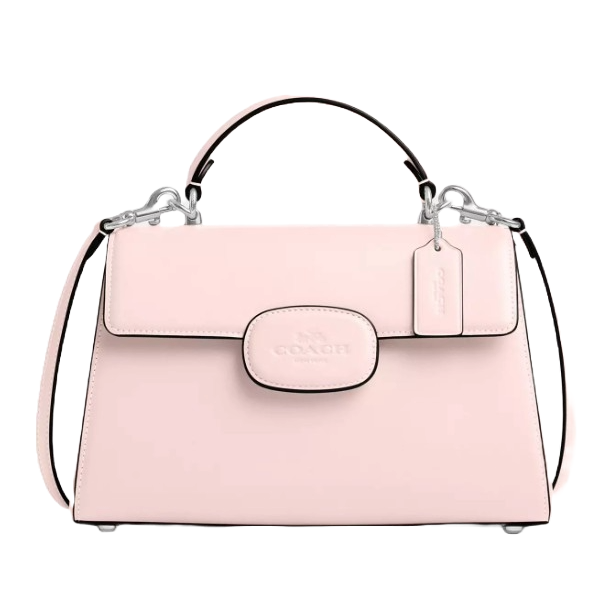 The Coach Eliza Top Handle Bag is a light pink structured handbag with a top handle and a detachable shoulder strap. It features silver-tone hardware, a front flap closure with the Coach logo, and a decorative tag hanging from the handle.