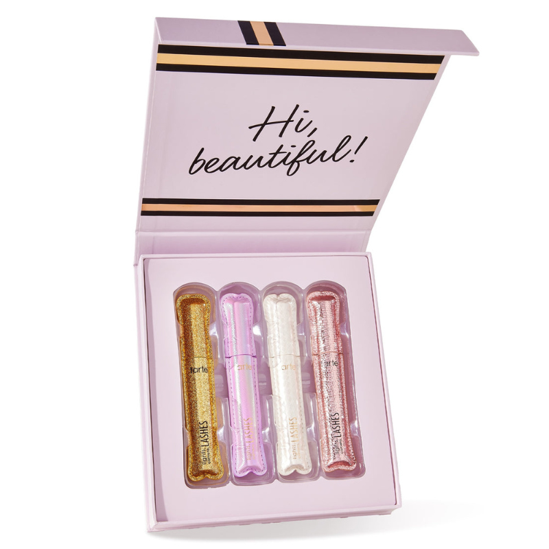 A box containing four tubes of mascara, each in different glittery colored packaging, with the message \“Hi, beautiful!\“ on the lid interior. Brands visible are Tarte and Lights, Camera, Lashes.