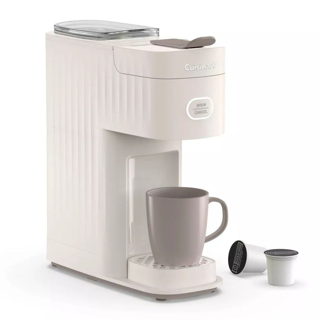 Cuisinart Single-Serve Coffee Maker in white with a compact design, featuring a button labeled \“Brew/Cancel.\“ It includes a coffee mug placed on the drip tray and two coffee pods nearby.