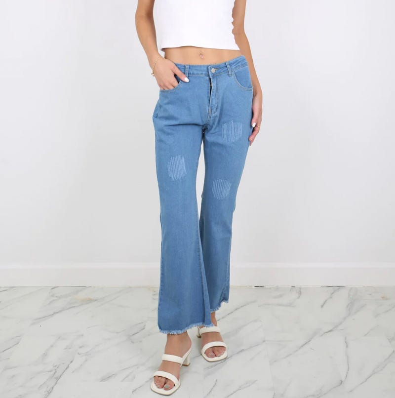 Light blue distressed wide-leg jeans and white open-toe sandals.