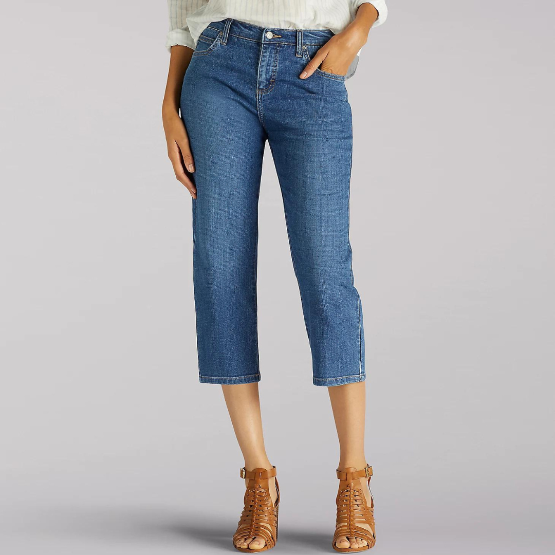 A pair of cropped blue denim jeans paired with brown strappy heeled sandals.
