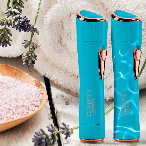 Two turquoise facial mist sprayers with copper accents, on a background of fresh lavender and a soft towel.