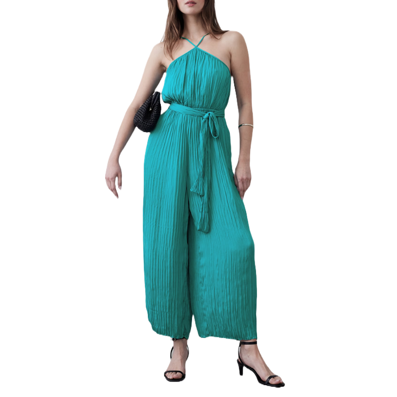 Teal halter-neck jumpsuit with a pleated texture, cinched at the waist with a matching tie belt. Paired with black heeled sandals and a black woven handbag.