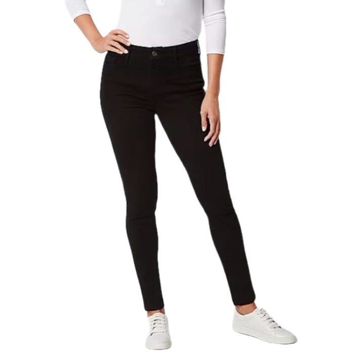 A person wearing black skinny jeans paired with a white long-sleeve shirt and white sneakers.