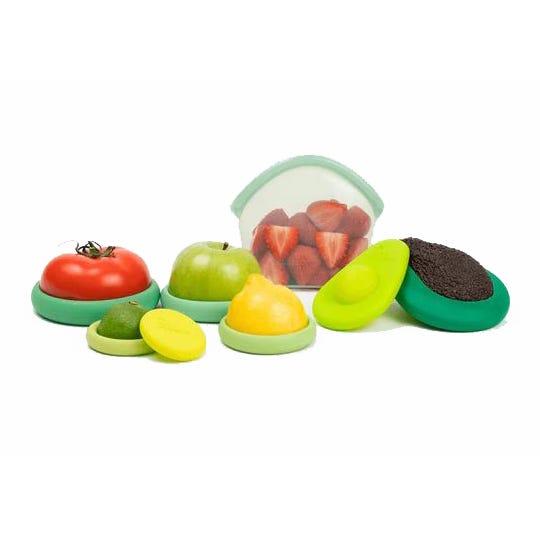 The 8pc Food Hugger Set includes various lids in different sizes and colors for sealing cut fruits and vegetables, featuring a reusable silicone pouch in the background with sliced strawberries.