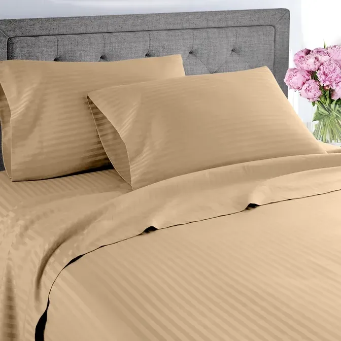 A tan striped bedding set with a fitted sheet, flat sheet, and two pillowcases on a bed.