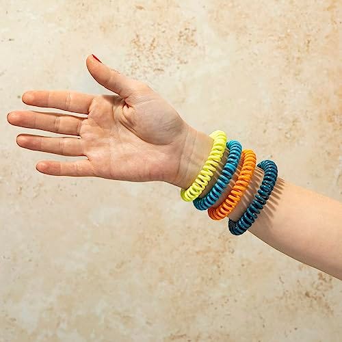 A person is wearing several spiral, colorful mosquito-repellent bracelets on their wrist.
