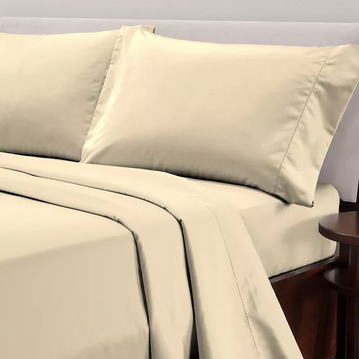 A set of beige bed sheets with pillowcases on a neatly made bed.