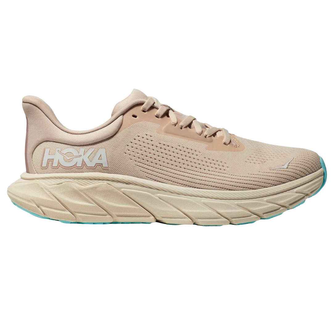 Hoka running shoe in beige with a thick cushioned sole and light blue accents, featuring the Hoka logo on the side.