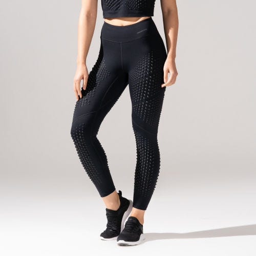 The leggings are high-waisted, black, with a textured pattern of raised dots covering the entire length. They're paired with matching athletic shoes.