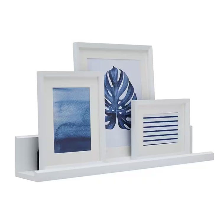 Three various-sized white picture frames on a white shelf, each displaying blue-toned artistic prints.