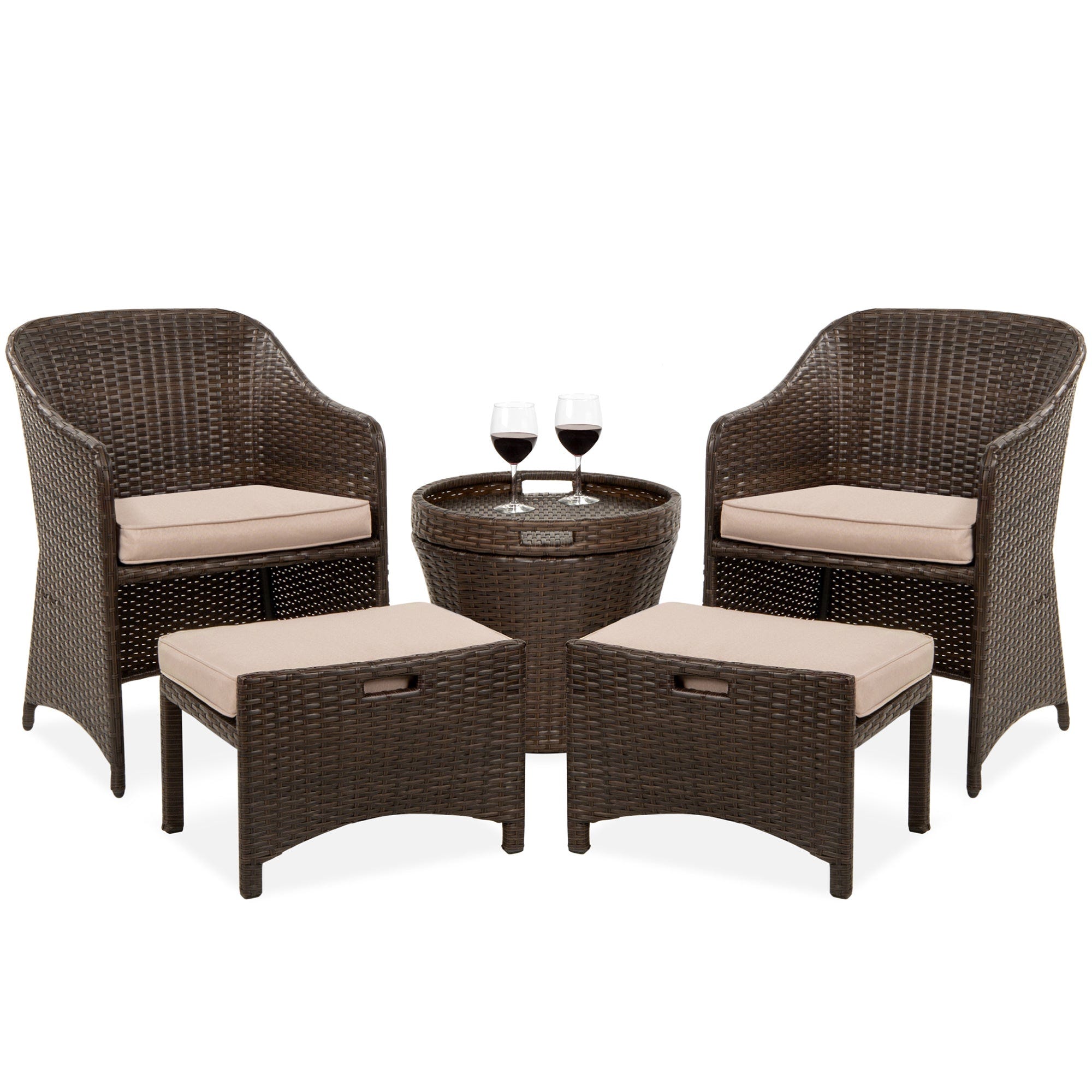 A five-piece patio set consisting of two wicker armchairs with beige cushions, two matching ottomans, and a round wicker table with a glass top and two wine glasses.