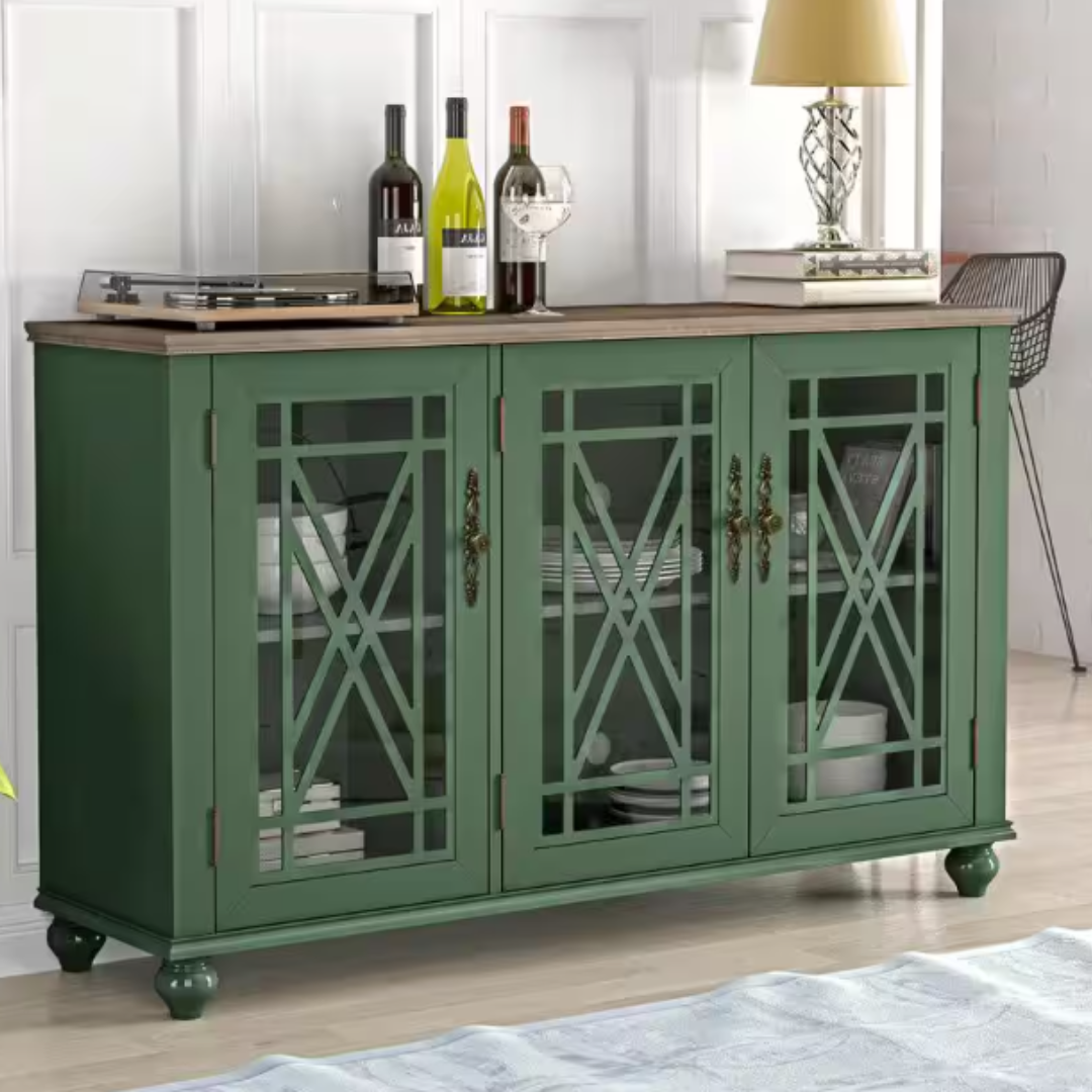 A green sideboard cabinet with glass doors, three wine bottles on top next to a lamp and books.
