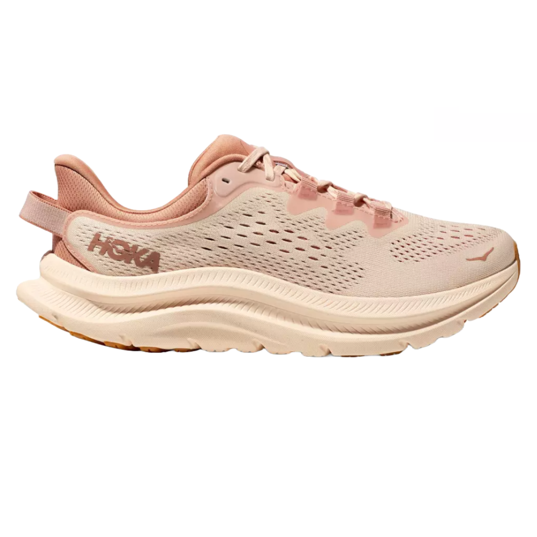 A HOKA running shoe in soft pink and beige tones with a thick, cushioned sole, designed for comfort and support.