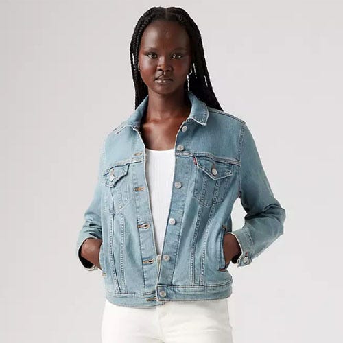 A woman wearing a light blue denim jacket and white top.