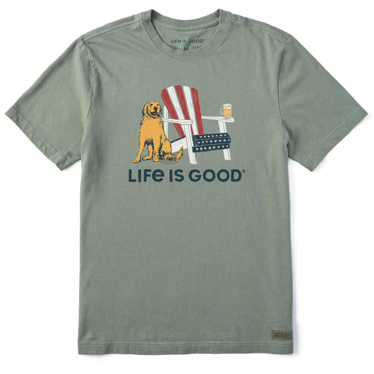 A green \“Life is Good\“ men's tee featuring a graphic of a cheerful dog sitting beside an Adirondack chair adorned with American flag colors and a mug of beer on the armrest.