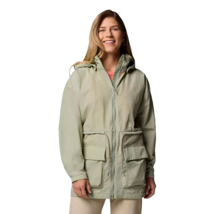 A woman wearing a light green hooded jacket with two large front pockets over a peach shirt and beige pants.