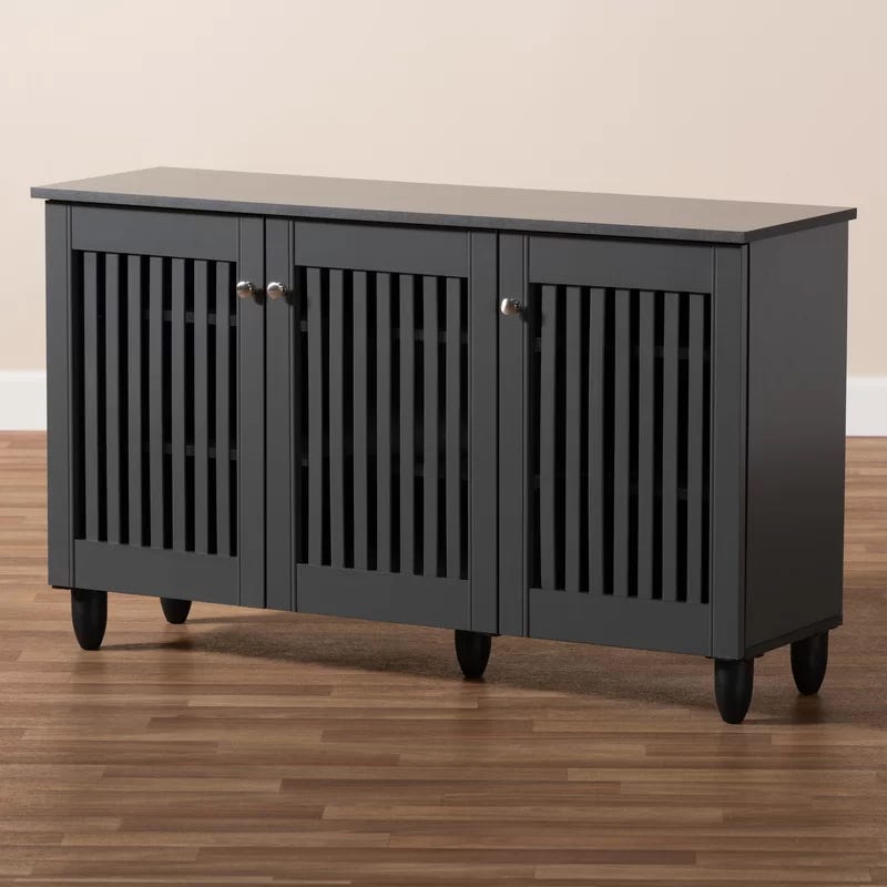 Black sideboard cabinet with vertical slats on cabinet doors and round knobs, standing on short, round feet.