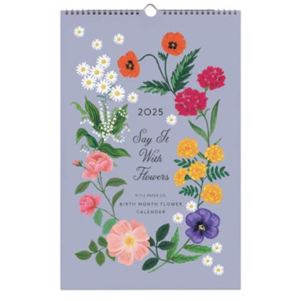 The Rifle Paper 2025 calendar features a \“Say It With Flowers\“ theme, displaying colorful illustrations of various flowers on a light purple background.