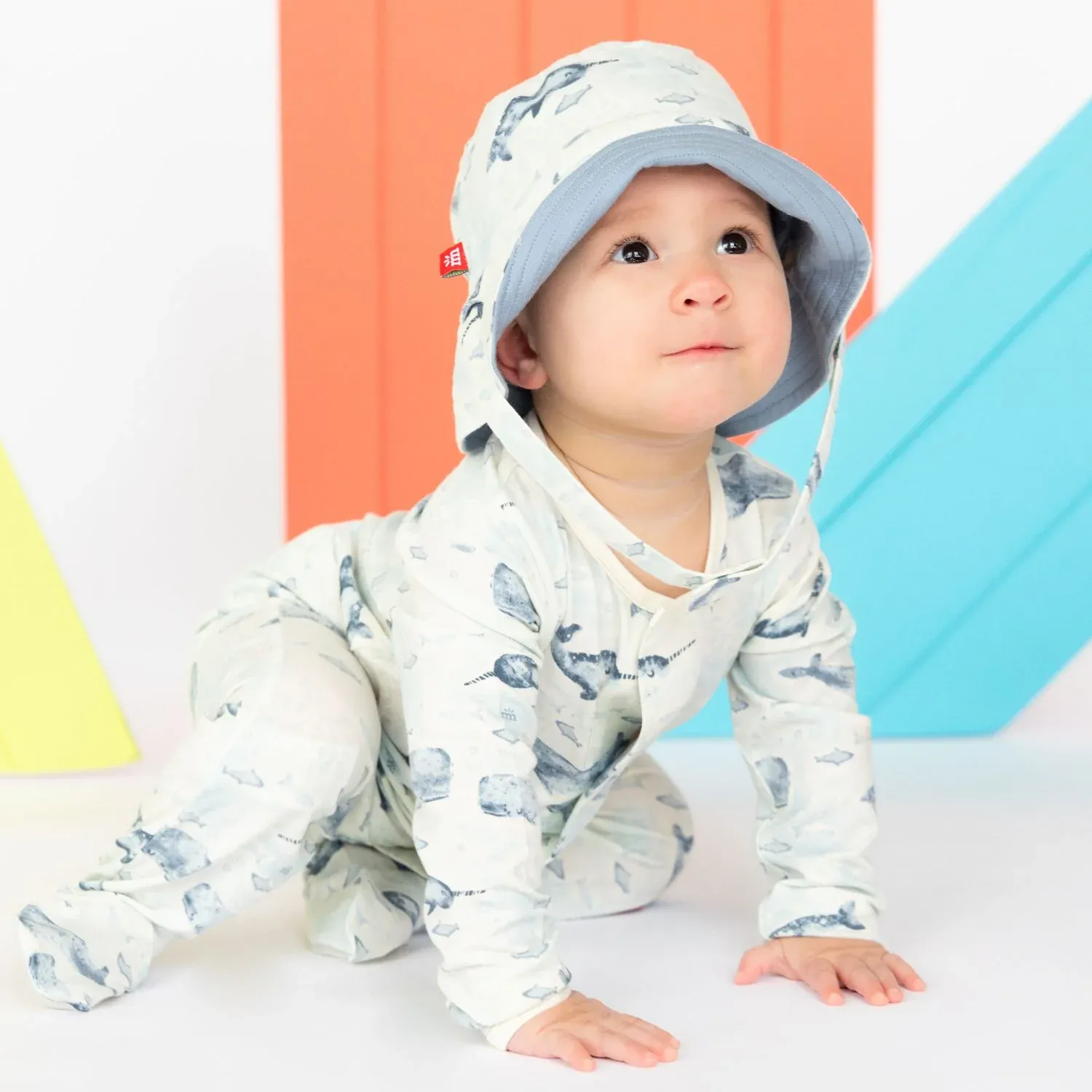 A baby wearing a printed onesie with a matching bucket hat.
