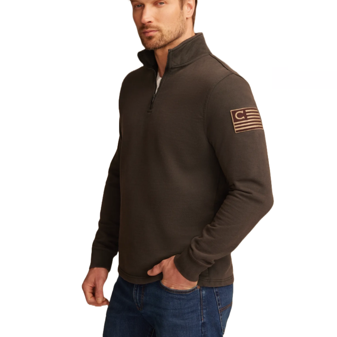A dark long-sleeve quarter-zip sweatshirt with a high collar, featuring a flag patch design on the left upper sleeve. It's paired with blue jeans.