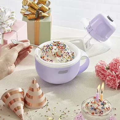 A Dash Mug Ice Cream Maker with a lavender lid is shown next to a mug of freshly made ice cream topped with sprinkles, with party decorations in the background.