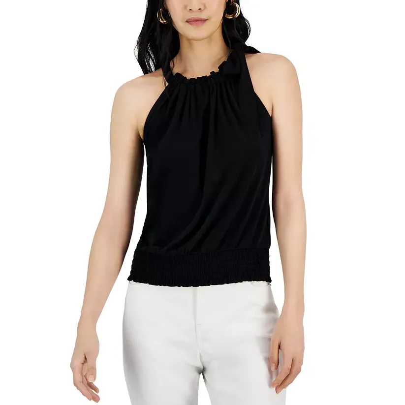 A woman is wearing a black halter top with a smocked waistband paired with white pants.