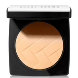Compact powder in a black and silver case with a textured surface, labeled \“Bobbi Brown.\“