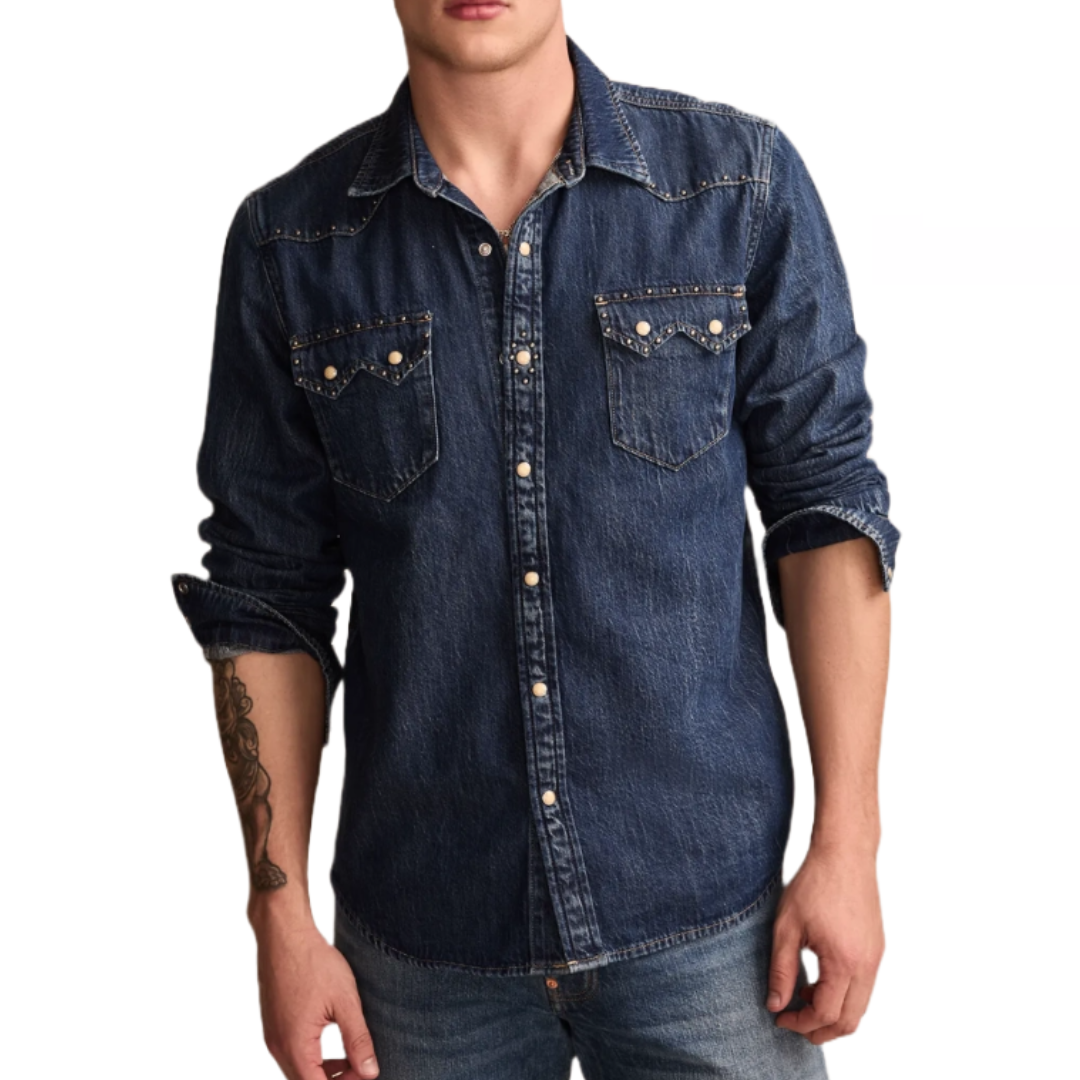 A denim shirt featuring studded detailing on the shoulders and front pockets, with a button-up closure and long sleeves, worn with sleeves slightly rolled up.