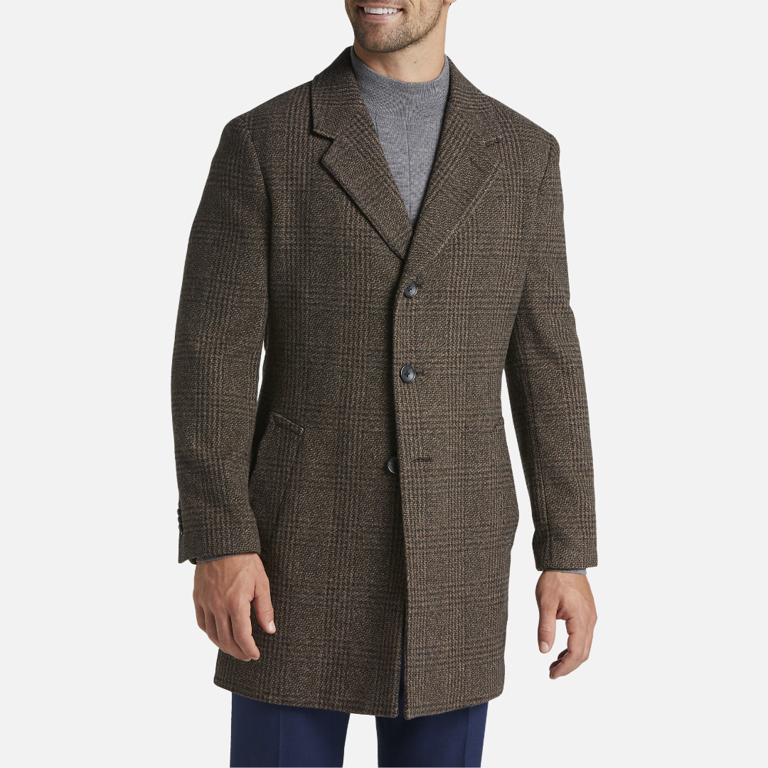 A man wearing a brown herringbone overcoat and a gray sweater.