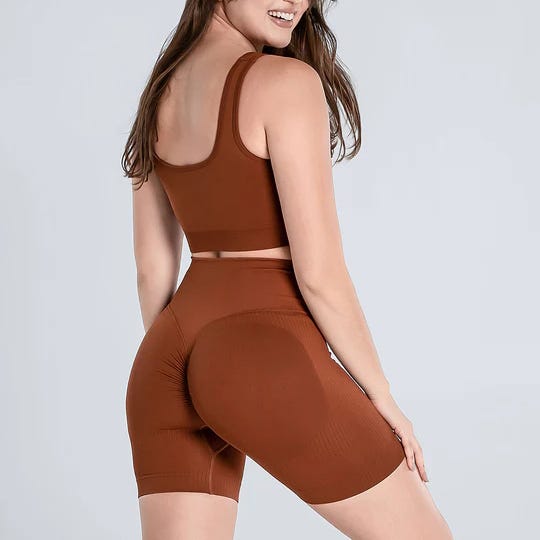 A woman is wearing a brown workout set consisting of a racerback top and high-waisted cycling shorts.