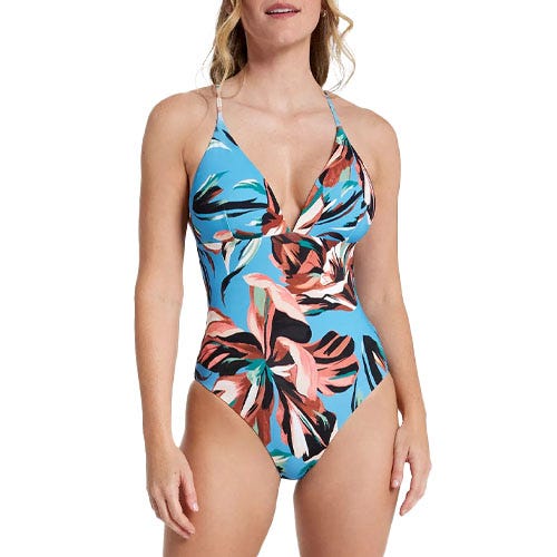 A floral one-piece swimsuit with a deep V-neckline, featuring a vibrant mix of blue, black, coral, and white colors in an abstract leaf pattern, and adjustable spaghetti straps.