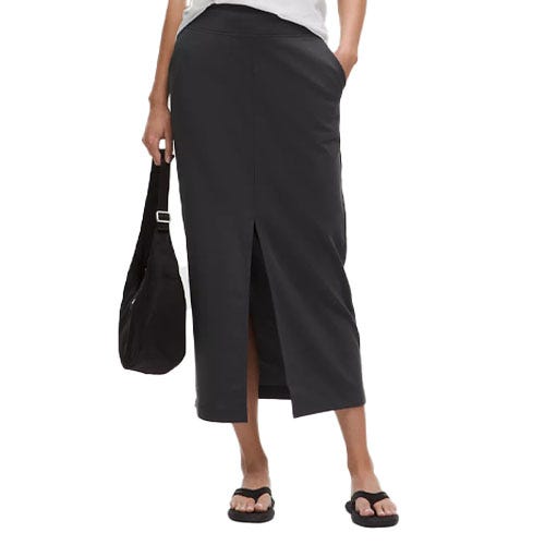 A black midi skirt with a front slit, paired with black sandals. The person is carrying a black shoulder bag.