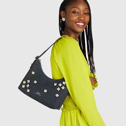 A woman in a lime green dress carrying a black shoulder bag with floral embellishments.