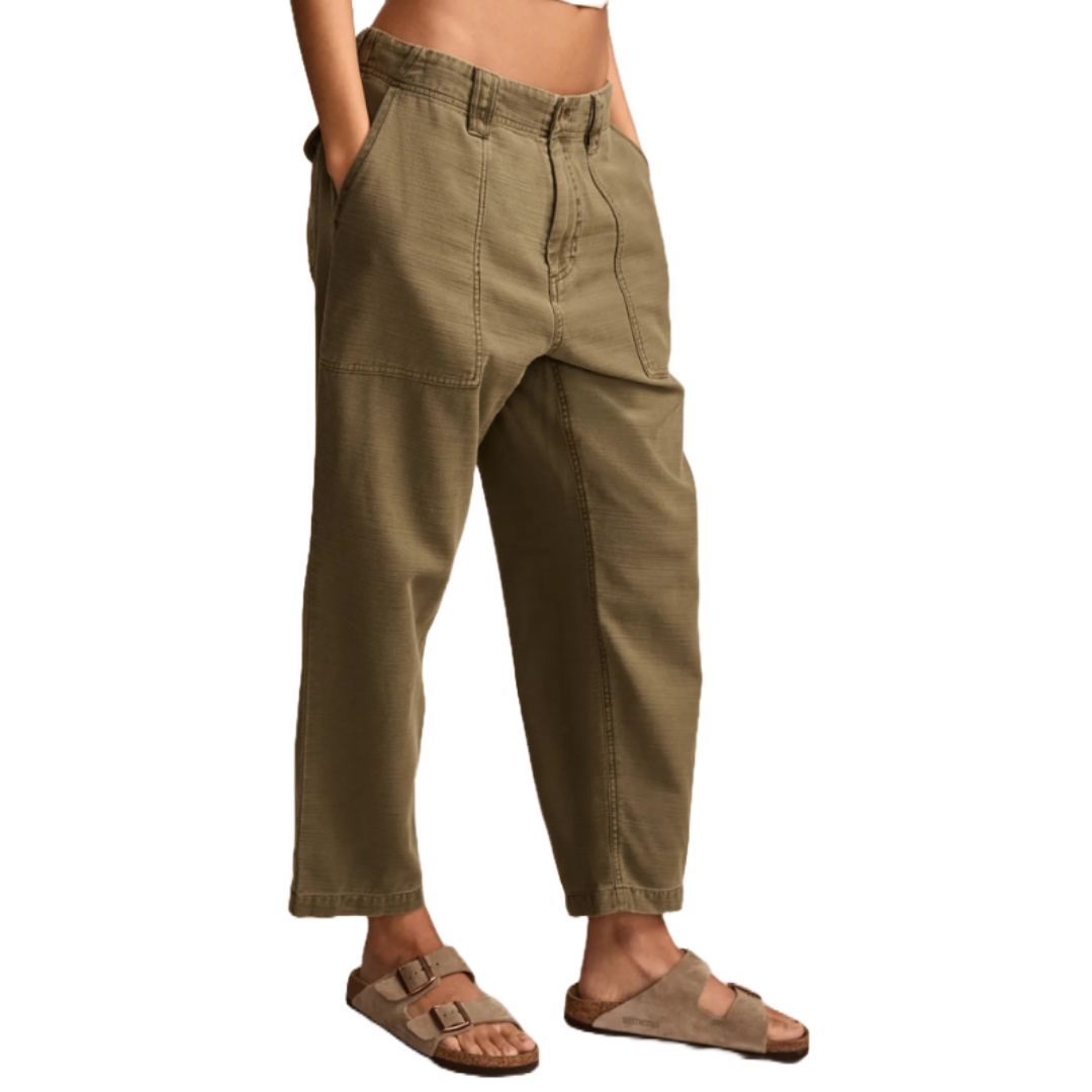 Olive green utility pants with an elastic waistband, featuring large front pockets and a relaxed, cropped fit. Paired with tan suede double-strap sandals.