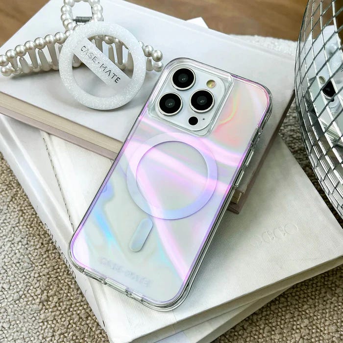 Iridescent phone case with a built-in MagSafe compatible ring on a table next to a pearl bracelet.