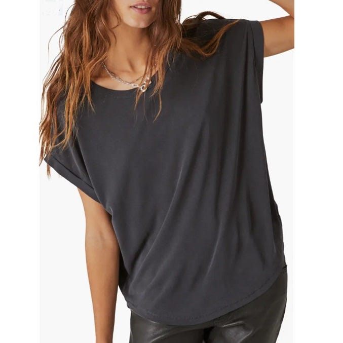 A woman wearing a loose-fitting black T-shirt and dark pants, paired with a chain necklace.