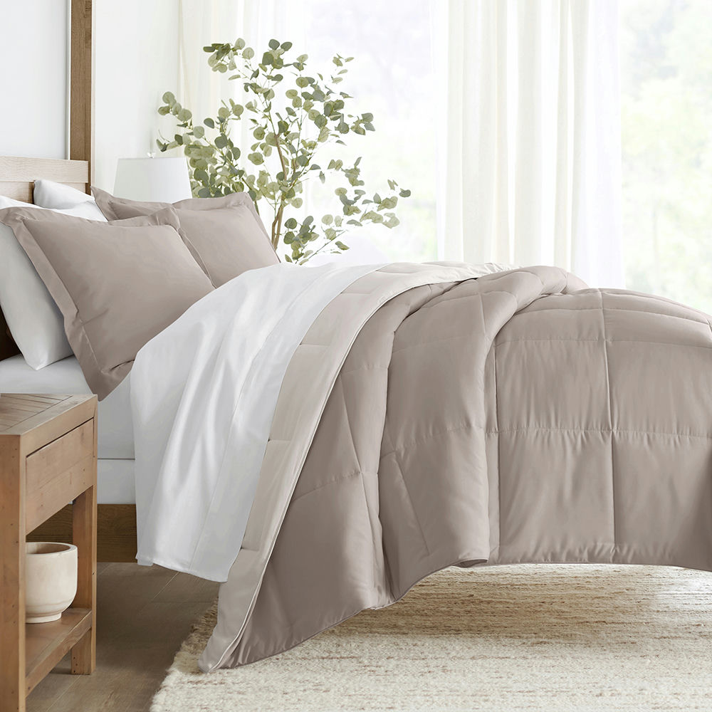 A bed with taupe and white bedding, including a duvet cover and pillowcases.