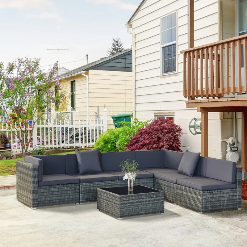 Outdoor sectional sofa with matching table, cushions in dark grey wicker design.